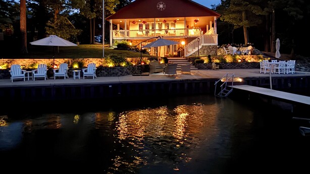 A waterfront property with a dock, outdoor seating, and a building with a red roof.