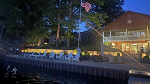 A waterfront property with a pool, lounge chairs, and a flagpole with an American flag.