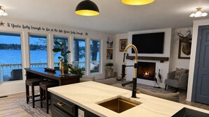 A modern kitchen with a large island, a fireplace, and a view of the lake.