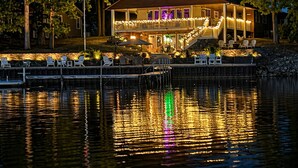 A waterfront property with a large house featuring a balcony, a dock, and an American flag.