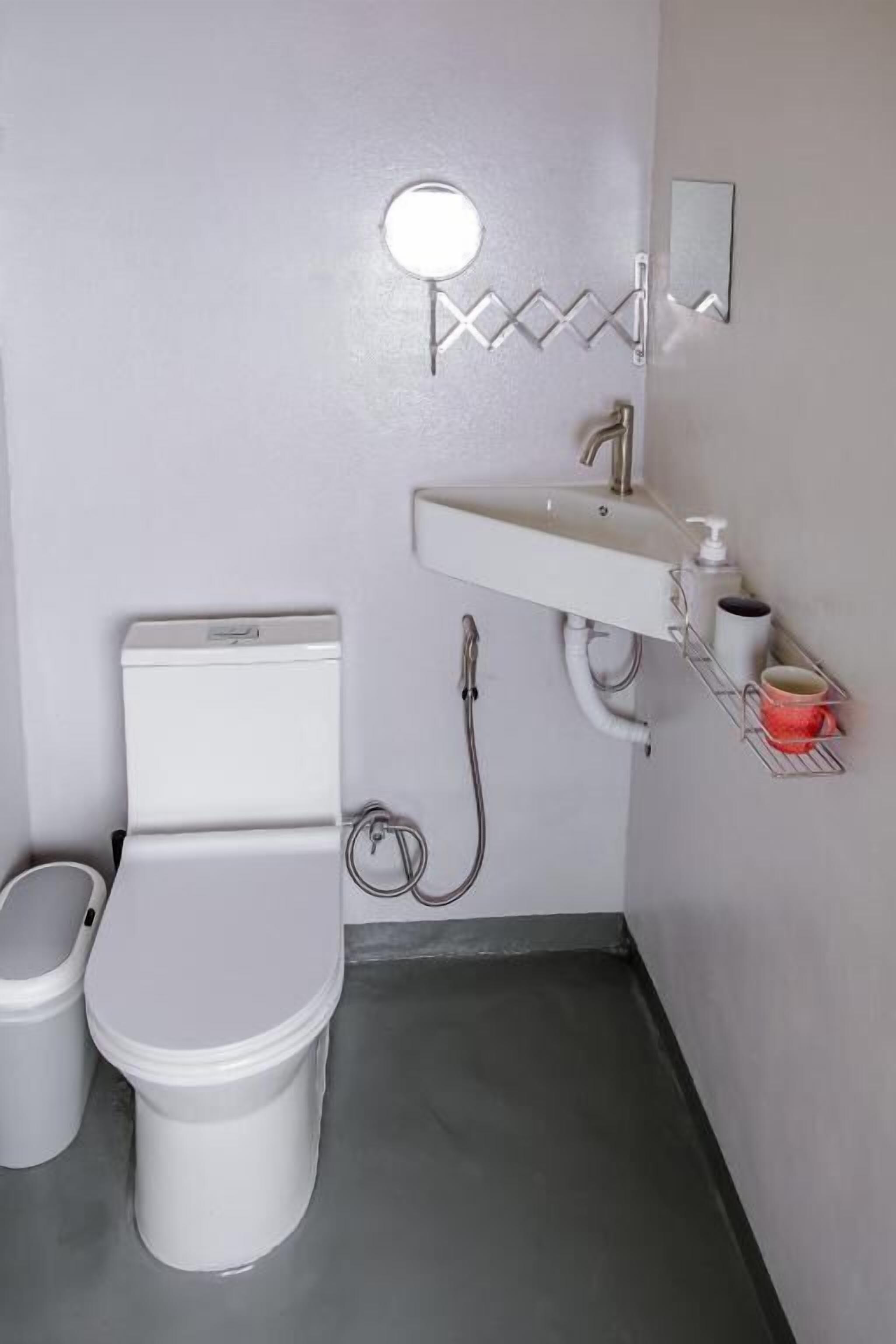 A small bathroom with a toilet, sink, and mirror.