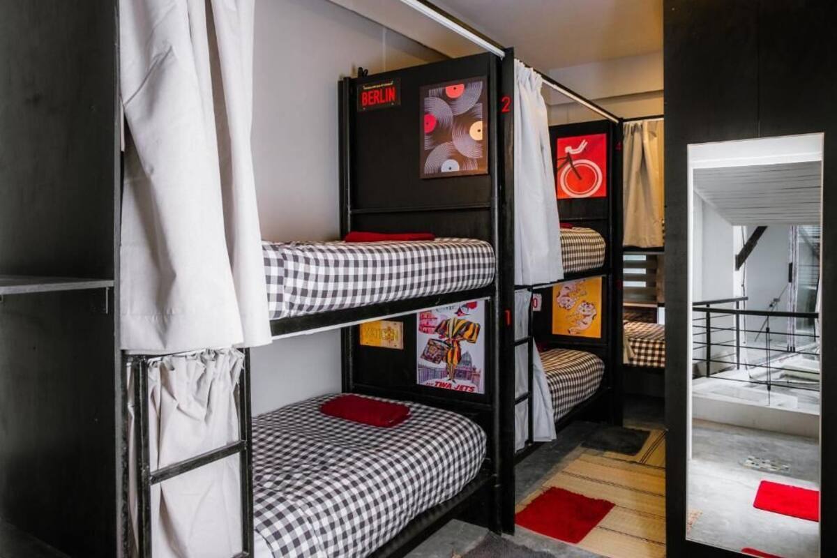 Une chambre de dortoir avec des lits superposés, une affiche de Berlin et un symbole représentant un vélo rouge.