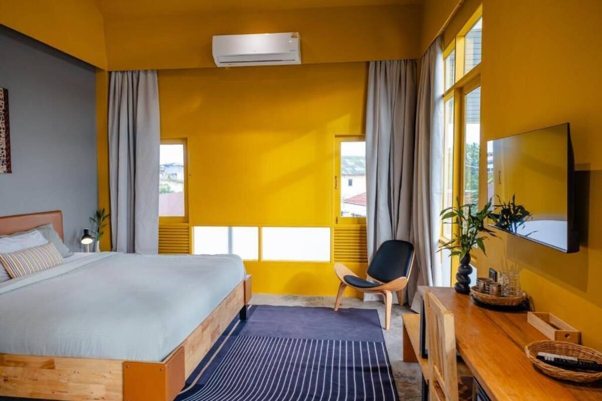 Une chambre d’hôtel avec un lit, un bureau, une chaise, une télévision et une fenêtre avec des rideaux.