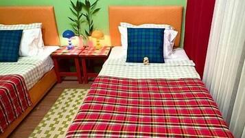 Una habitación con dos camas, una mesita de noche, una lámpara y un cartel en la pared.