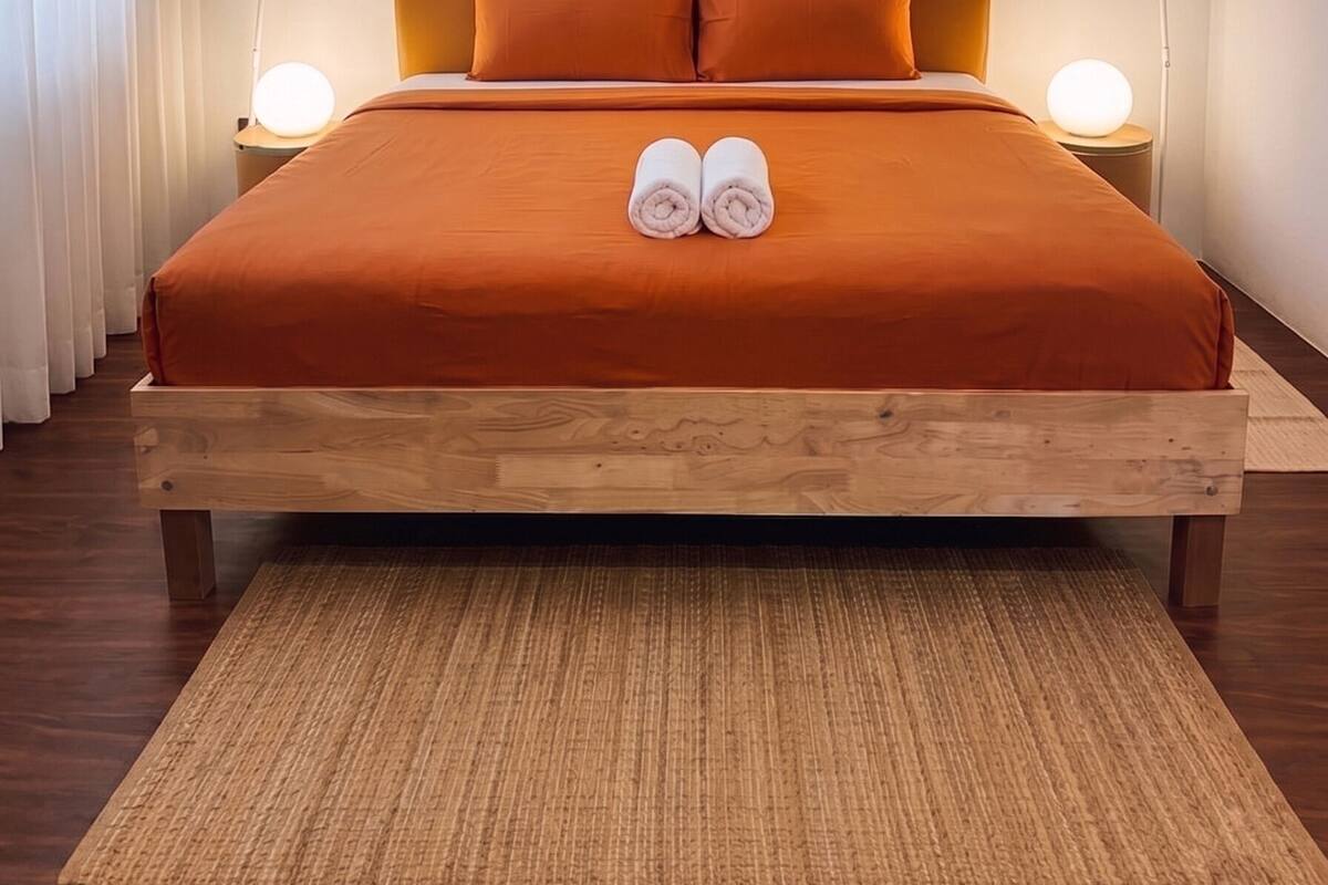 Un lit bien fait, avec deux oreillers, une tête de lit en bois et deux lampes de chevet.