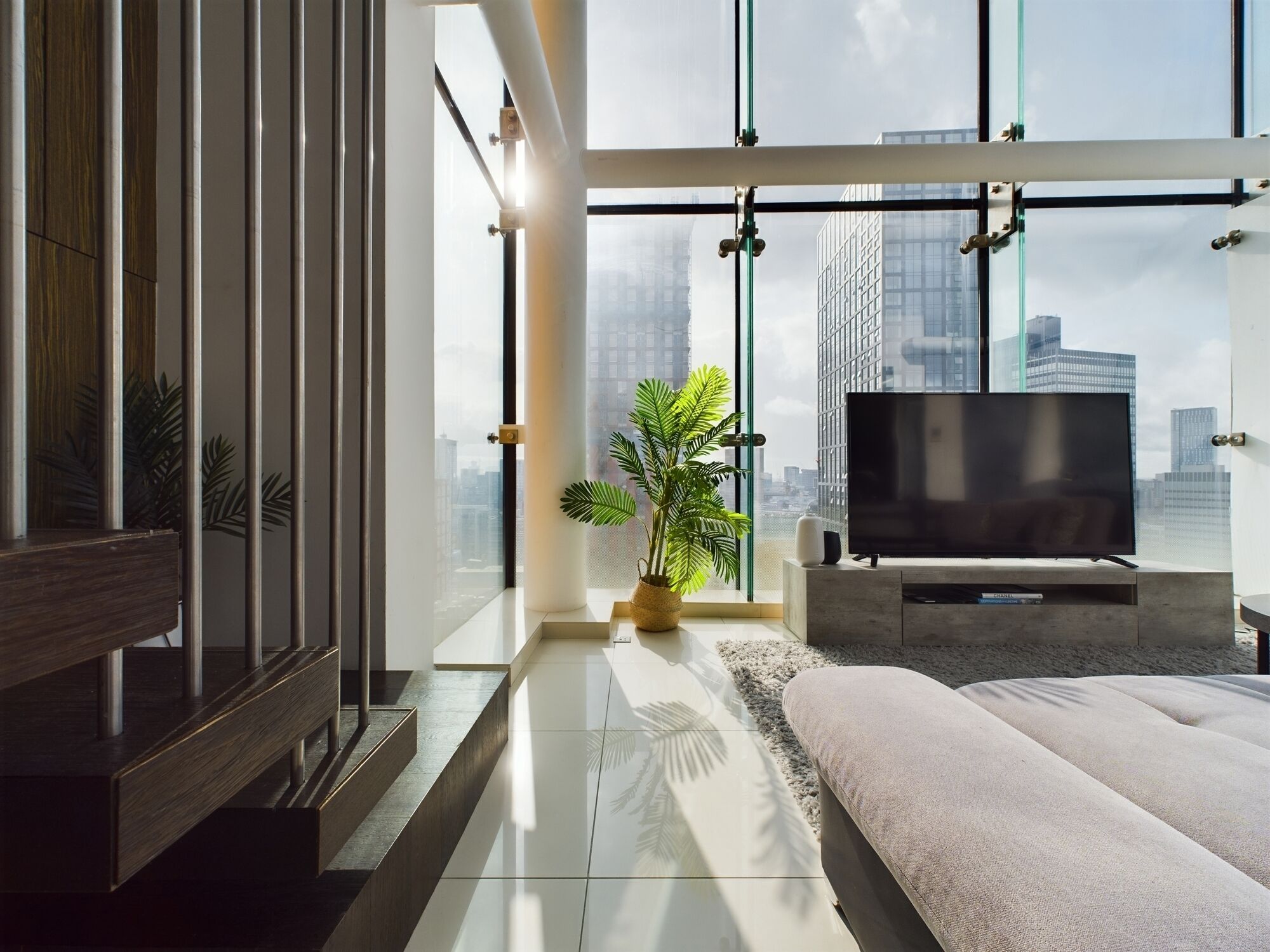Een moderne slaapkamer met een groot raam, een flatscreen televisie en een potplant.