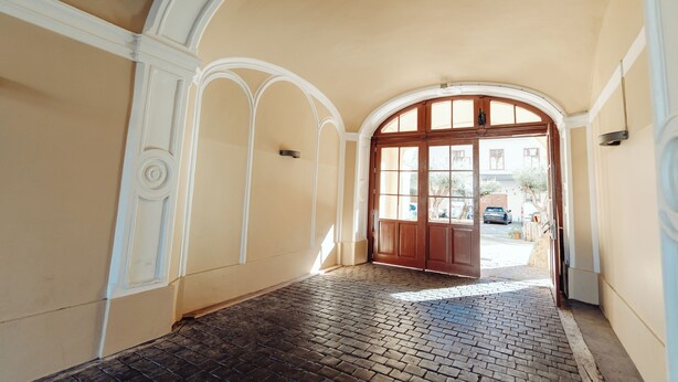 An arched hallway with a brick floor and a wooden door leading outside. - Lilians cozy apartment JAKO 3a (Graz)