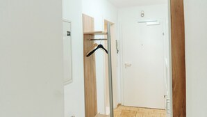 A hallway with a wooden door, a coat rack, and a light switch on the wall. - Lilians cozy apartment JAKO 3a (Graz)