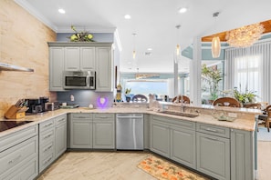 A modern kitchen with grey cabinets, a built-in microwave, and a dishwasher. - Southern Dream: Two Units (Fort Myers Beach)