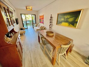 Ein geräumiges Zimmer mit einem Holztisch, Stühlen, einer Couch und einem großen Fenster.