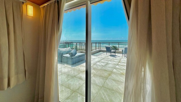 Un balcon avec vue sur l’océan, doté de sièges confortables et d’une balustrade.
