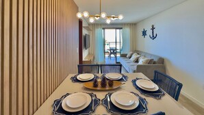 Un coin repas avec une table dressée pour quatre personnes, un canapé et un téléviseur en arrière-plan.