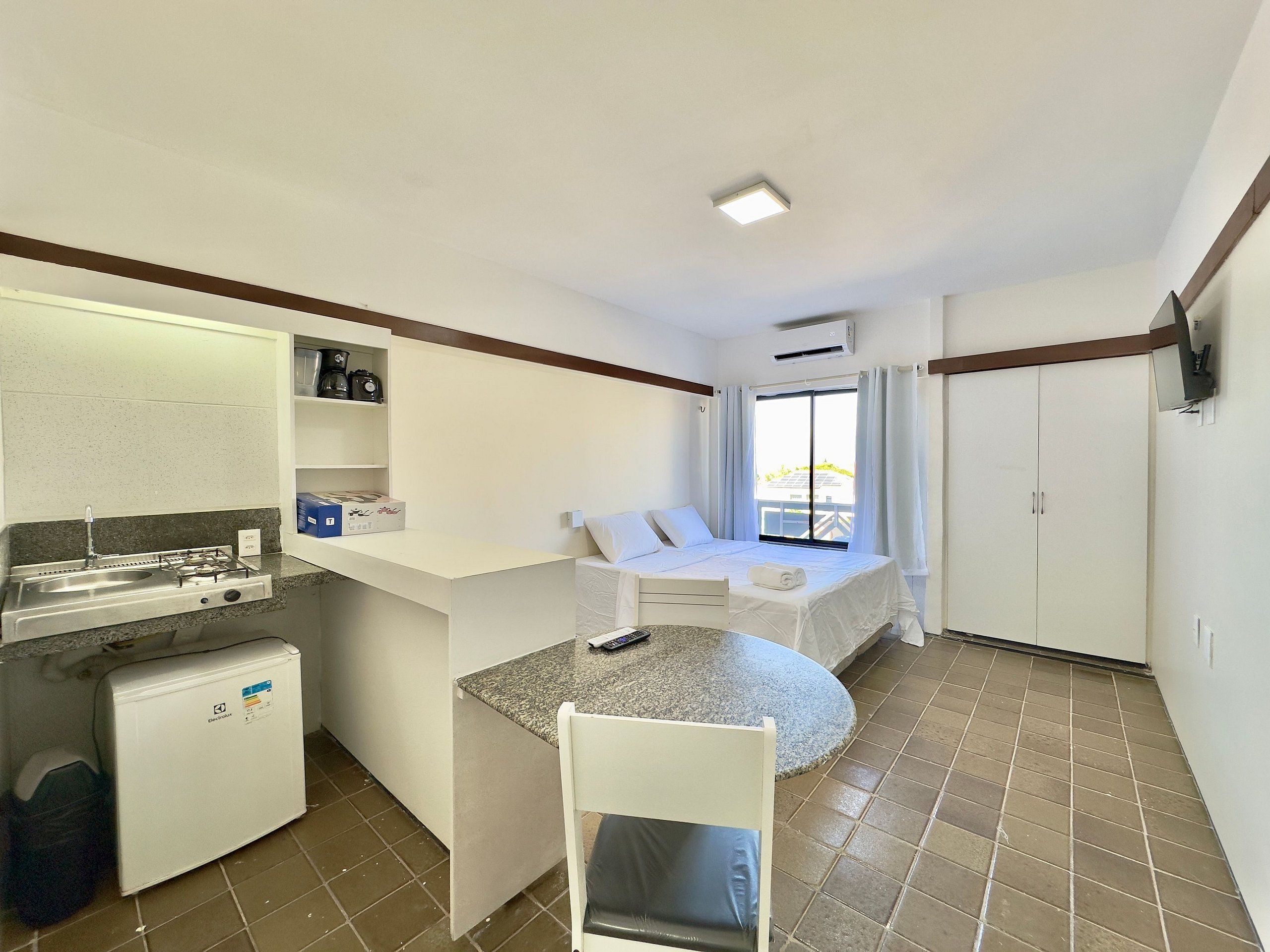 Habitación de hotel compacta con kitchenette, cama con vistas y un pequeño comedor.