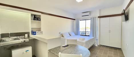 Habitación de hotel compacta con kitchenette, cama con vistas y un pequeño comedor.