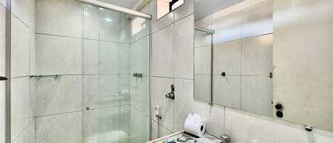 A modern bathroom with a glass shower enclosure, a marble sink, and a large mirror.