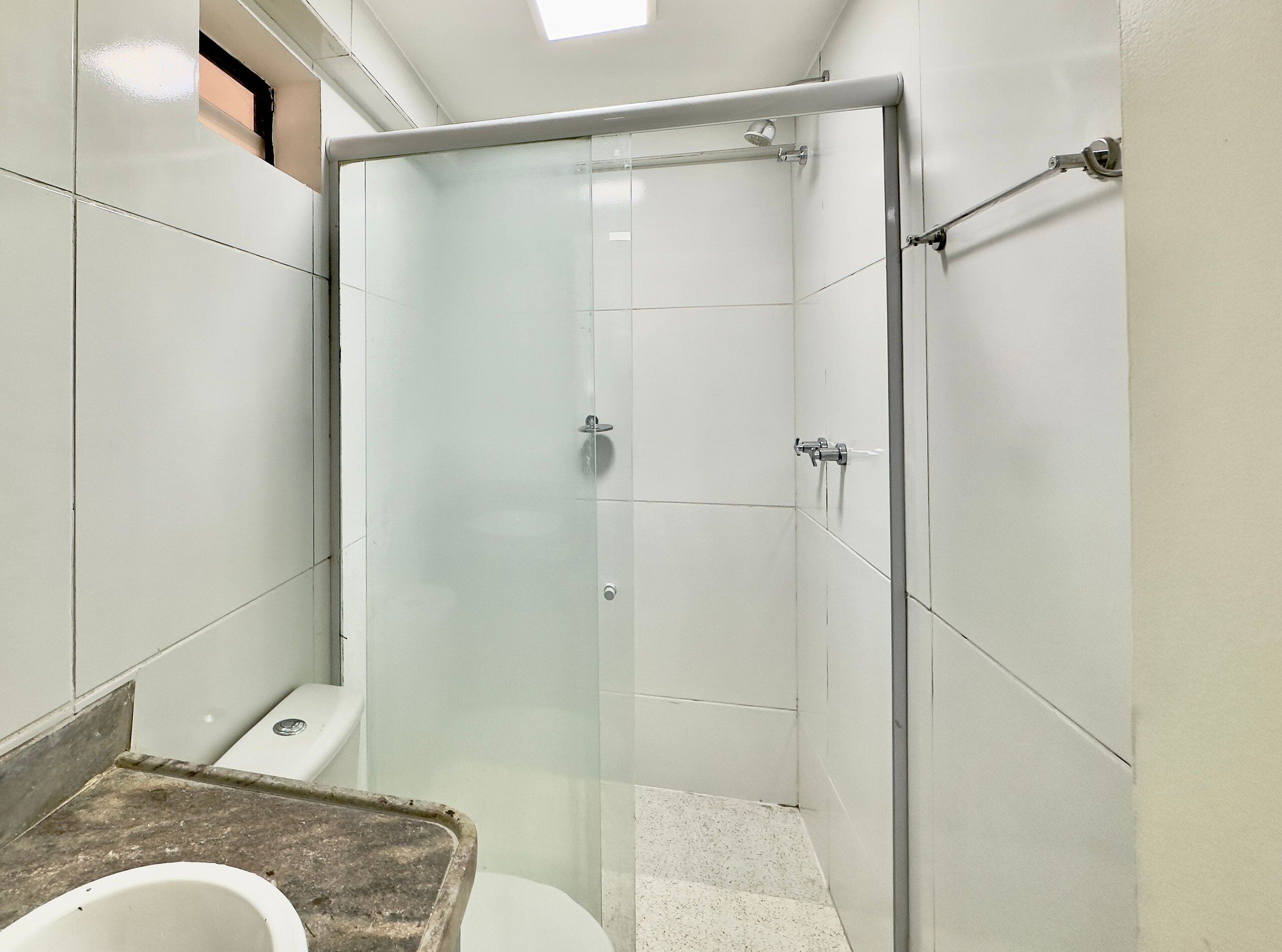 Een badkamer met een douchecabine van glas, een toilet en een wastafel.