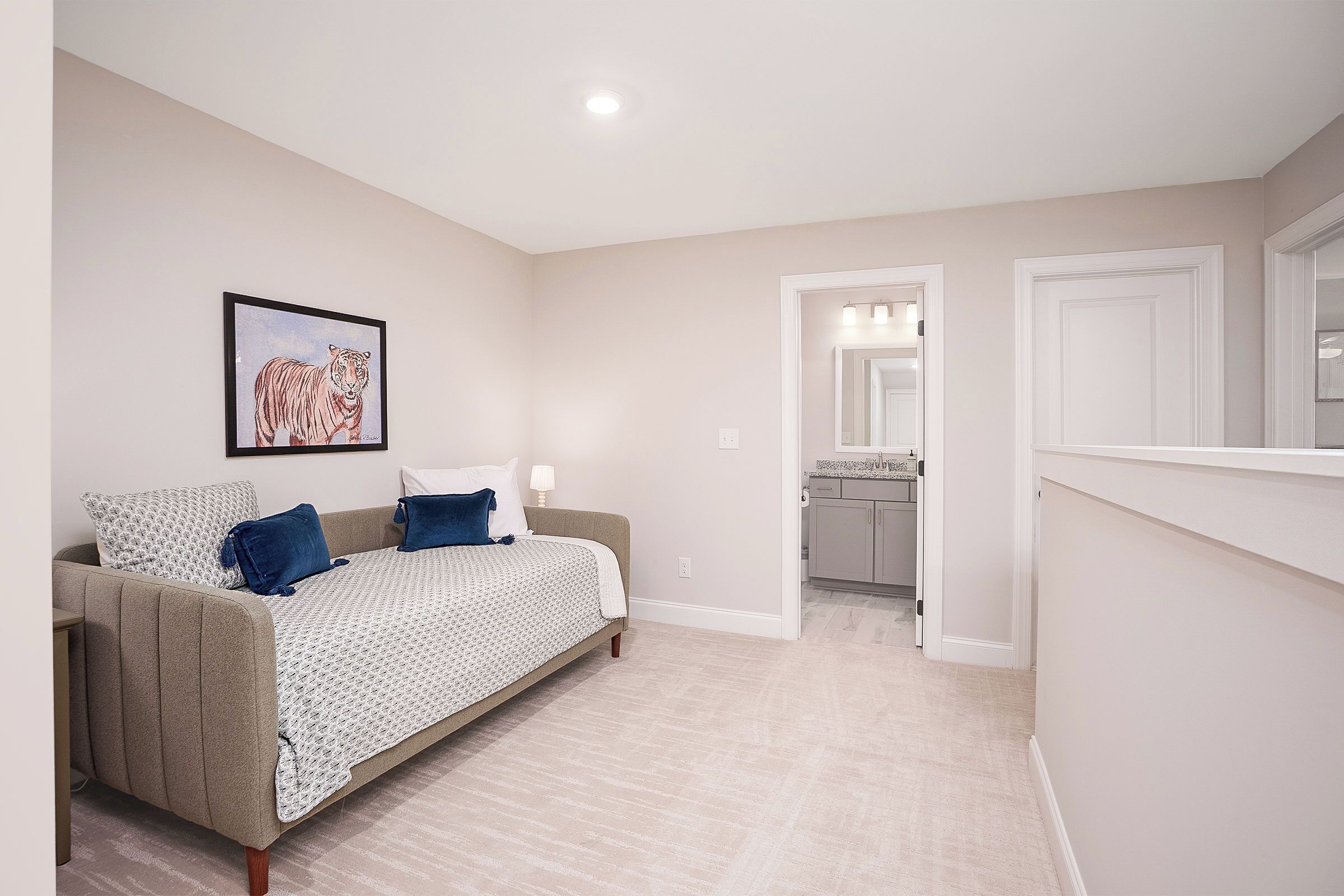 A bedroom with a bed, a framed picture on the wall, and a doorway leading to a bathroom.