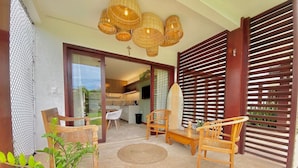 A patio with wicker furniture, a surfboard, and a TV in the background. - Taiba Beach Resort por Be My Guest! (São Gonçalo do Amarante)