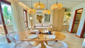 A dining area with a round table, white chairs, and hanging wicker lamps. - Taiba Beach Resort por Be My Guest! (São Gonçalo do Amarante)