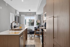 Una cocina moderna con una isla central, un área de comedor con sofá y mesa, y vistas al exterior.