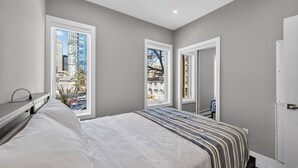 Ein Schlafzimmer mit einem Bett, einem Schreibtisch und einem Fenster mit Blick auf die Stadt.