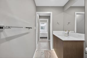 A modern bathroom with a double sink, a large mirror, and a walk-in shower. - Luxury 2BR | Near Stampede | Modern | AC (Calgary)