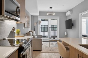 Una cocina moderna con horno integrado, un comedor con mesa redonda de vidrio y un sofá.