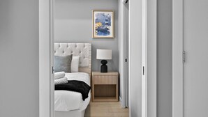 Um quarto com cama, mesa de cabeceira, luminária e um quadro na parede.