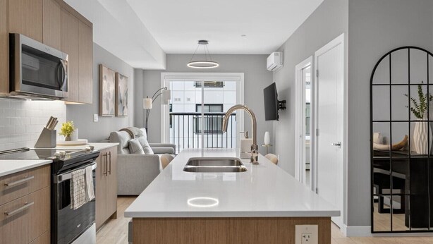 Cozinha moderna com ilha central, eletrodomésticos embutidos e vista para a sala de estar.