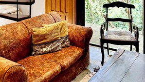 Un intérieur en bois comprenant un canapé, un banc, un escalier et une porte donnant sur un espace extérieur arboré.