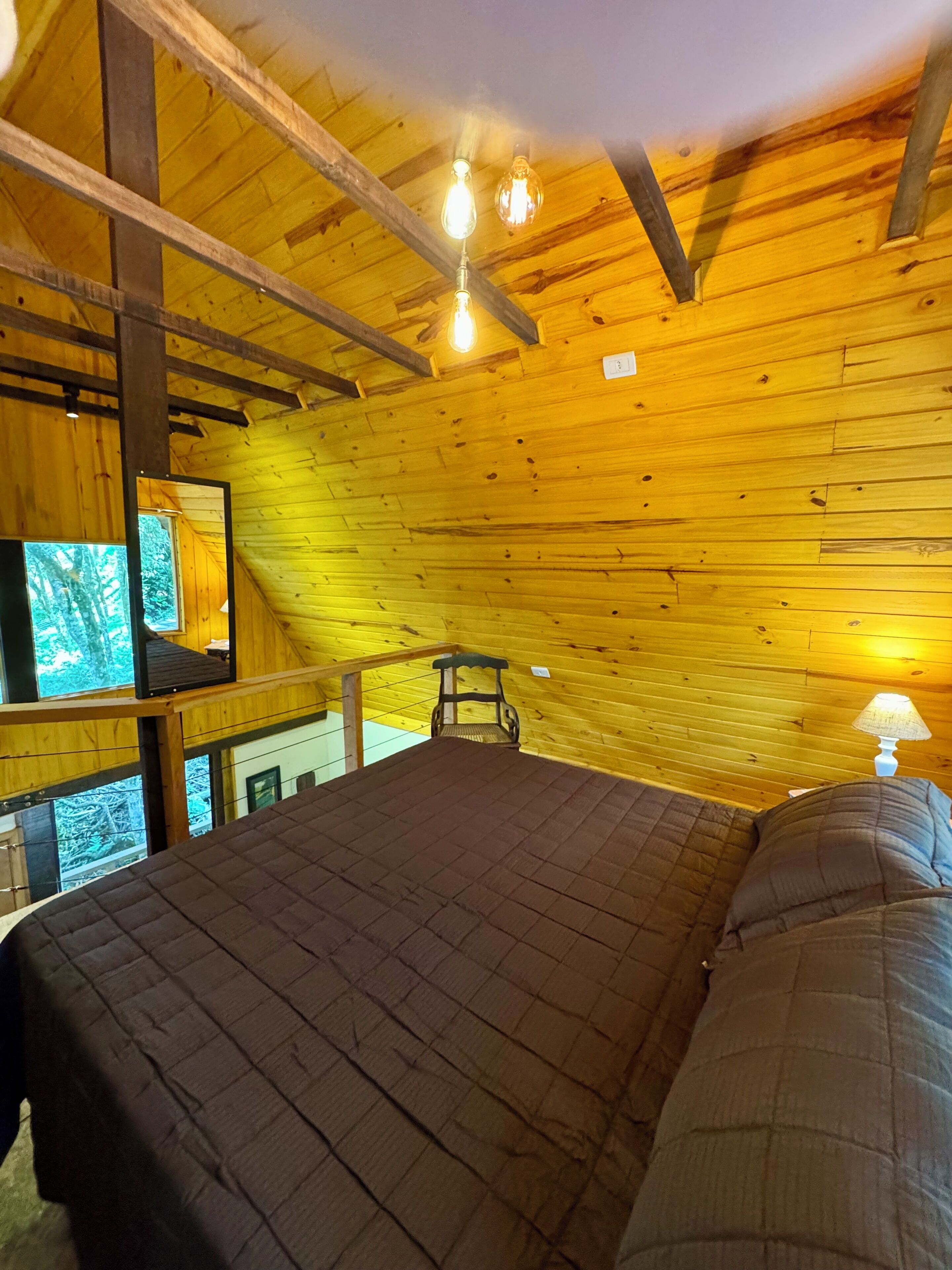 L'interno di una baita in legno con un letto, una sedia e un tavolo.