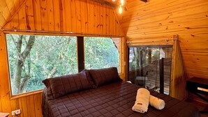 Une chambre dans une cabane en bois, avec un grand lit, une fenêtre et un plafond en bois.