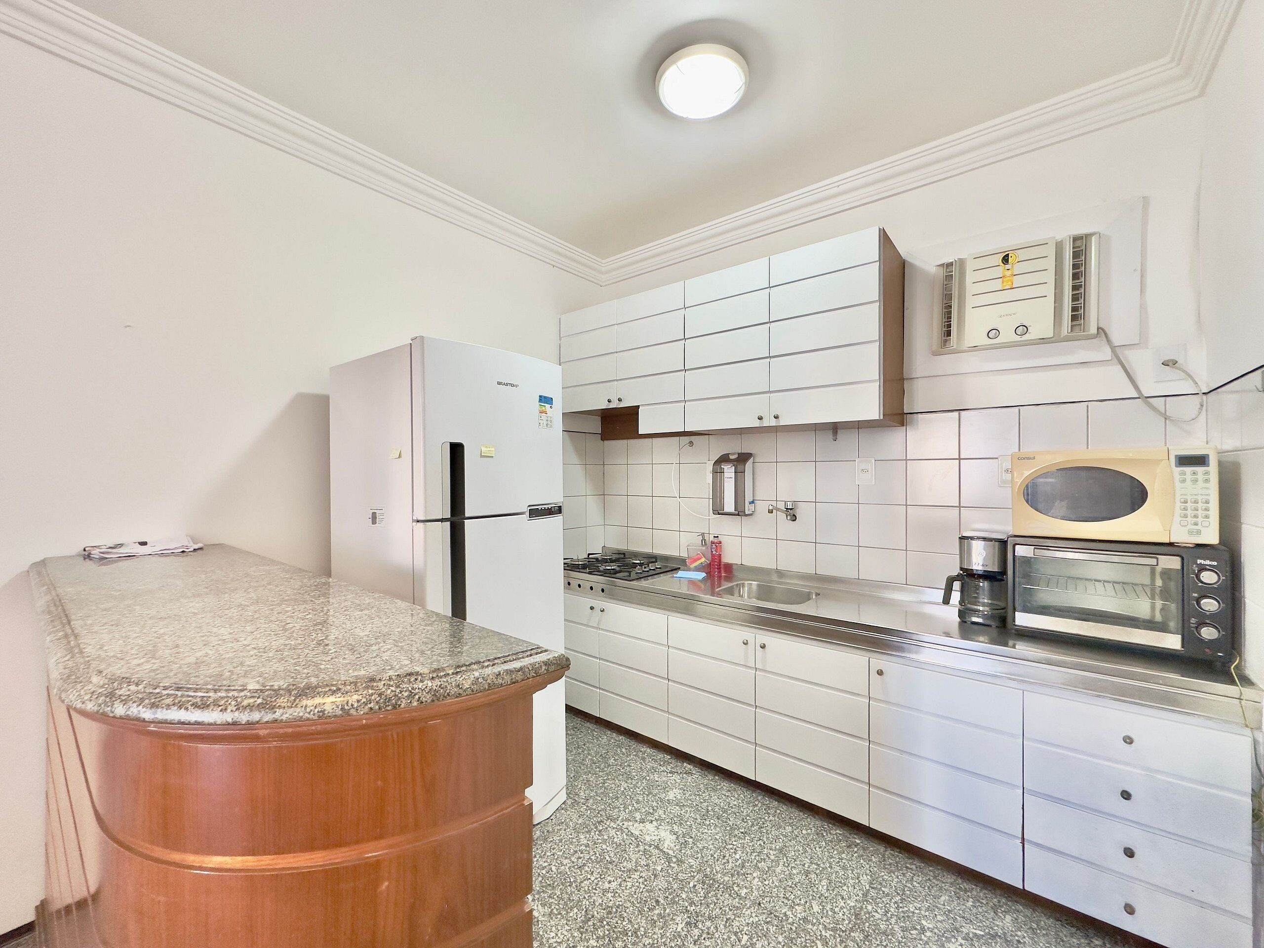 A compact kitchen with a refrigerator, microwave, toaster, and a sink.