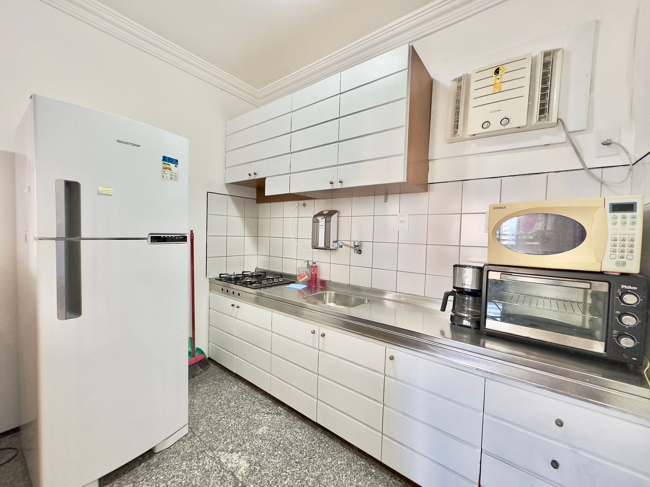 Una cocina con un refrigerador blanco, estufa a gas, microondas y un lavamanos.