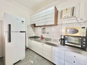 Una cocina con un refrigerador blanco, estufa a gas, microondas y un lavamanos.