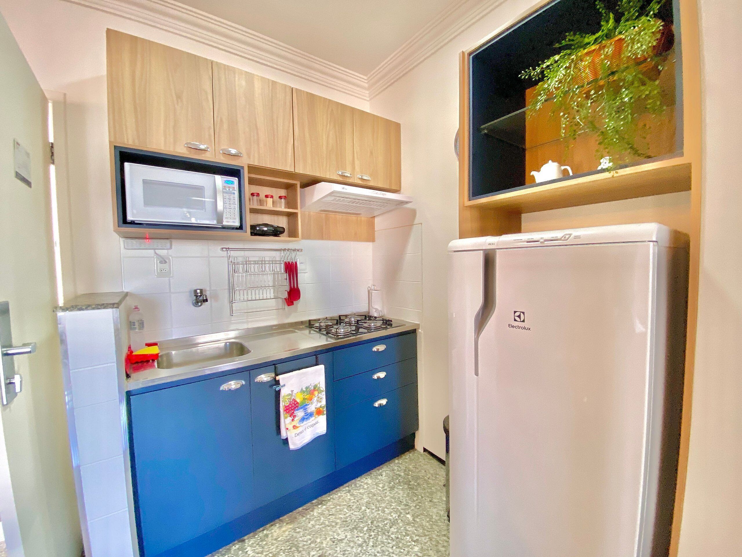 Una cocina compacta equipada con microondas, estufa, lavaplatos y refrigerador.