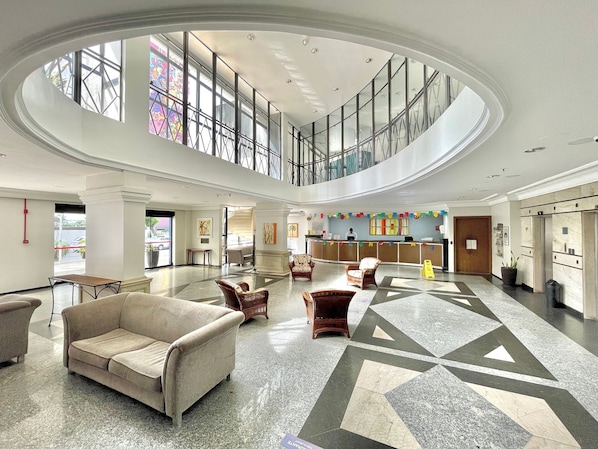 A spacious lobby with a high ceiling, a reception desk, seating areas, and a view through a large window. - Flat no Saint Martin (Fortaleza)