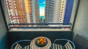 Un balcón con dos sillas y una mesa con un frutero.