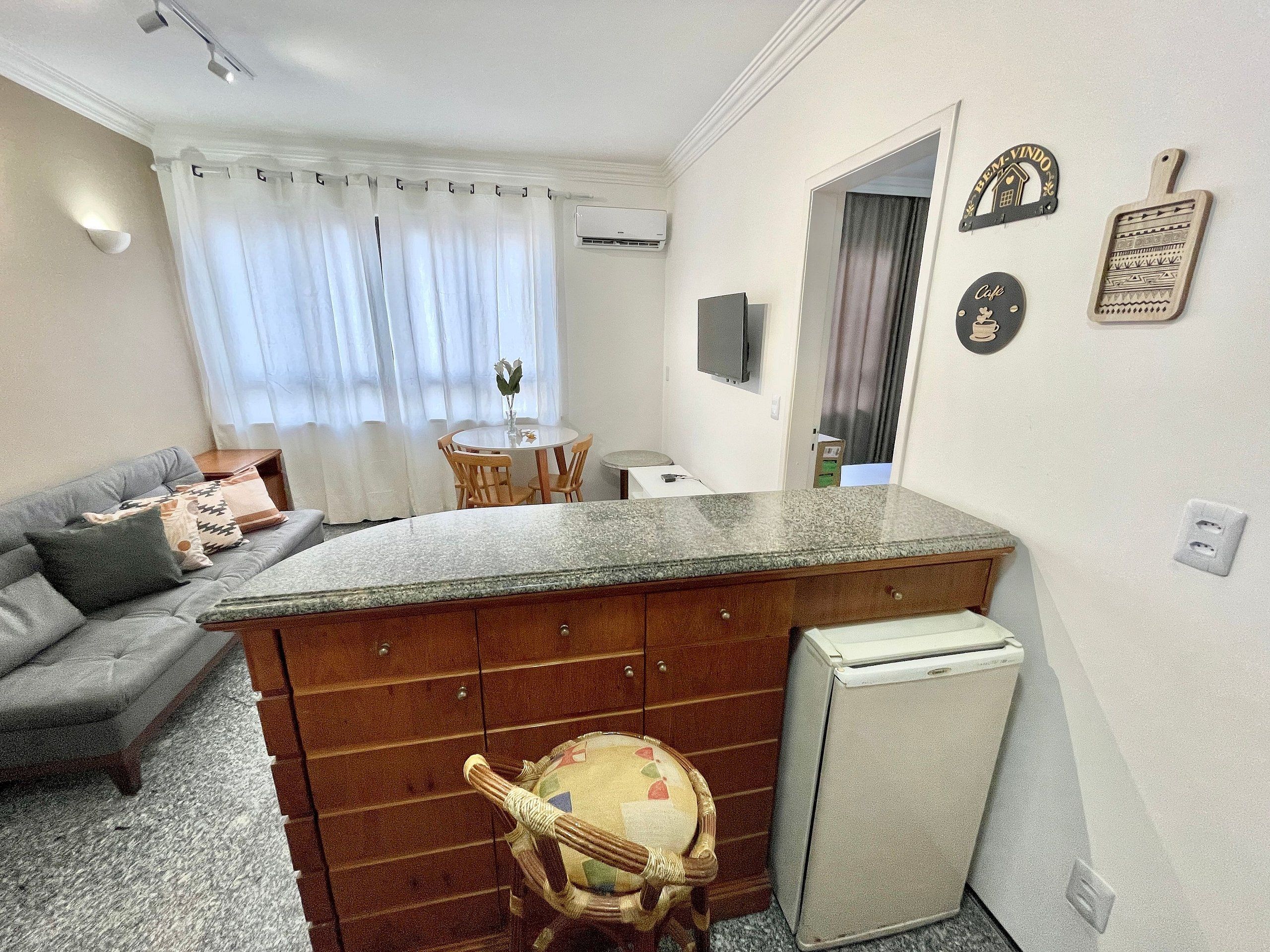 Um espaço compacto para viver, com cozinha compacta, área de refeições e sofá.