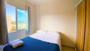 Een hotelkamer met een bed, een raam met gordijnen en uitzicht op buiten.
