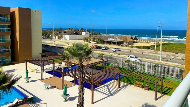 Een hotel met zwembad, terras en uitzicht op strand en zee.