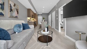 Ein modernes Wohnzimmer mit grauem Sofa, einem Couchtisch und einem flachbildfernseher an der Wand.