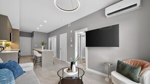 Ein modernes Wohnzimmer mit einer Couch, einem Couchtisch und einem an der Wand montierten Fernseher.
