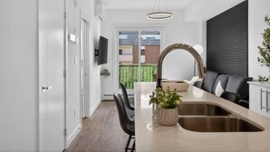 A modern kitchen with a large island, a built-in oven, and a large window. - 2BR | DT | Balcony | AC | Mins to Saddledome (Calgary)