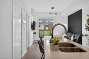 A modern kitchen with a large island, a built-in oven, and a large window. - 2BR | DT | Balcony | AC | Mins to Saddledome (Calgary)