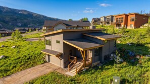 A modern two-story house with a covered porch and a staircase leading to the entrance. - Summit County Gem |  Designer Kitchen + Great Views (Silverthorne)
