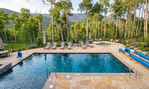 A swimming pool with a stone deck, lounge chairs, and a hot tub. - Summit County Gem |  Designer Kitchen + Great Views (Silverthorne)