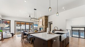 A modern kitchen with a large island, dining area, and a view of the outdoors. - Summit County Gem |  Designer Kitchen + Great Views (Silverthorne)