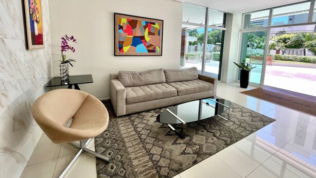 A modern living room with a sofa, a glass coffee table, a chair, a rug, and artwork on the walls. - Condominio Vivence (Fortaleza)