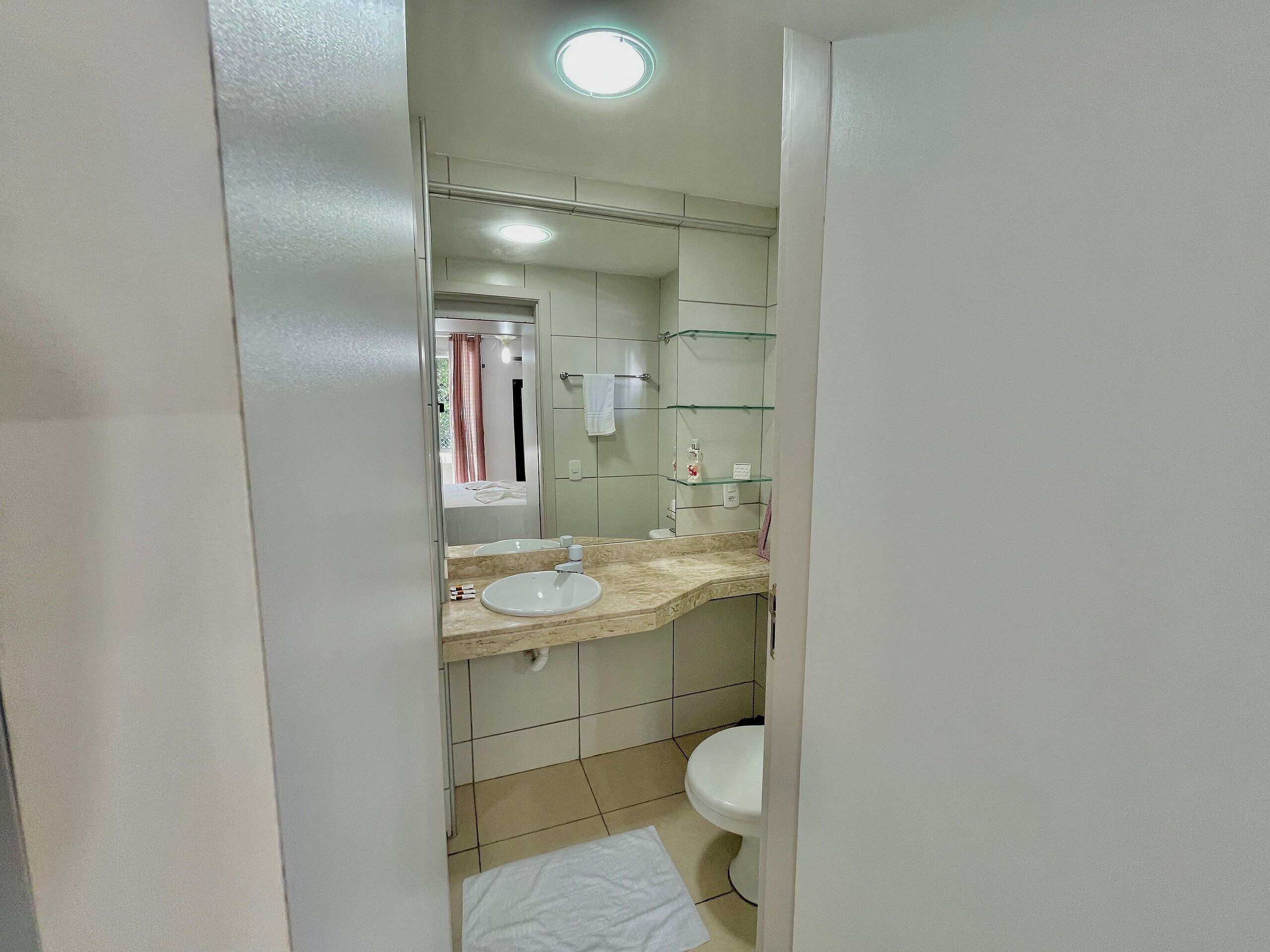 Une salle de bain équipée d’un lavabo, d’un miroir, de toilettes et d’étagères en verre.